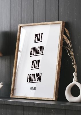 An unframed print of stay hungry stay foolish quote in typography in white and black accent colour
