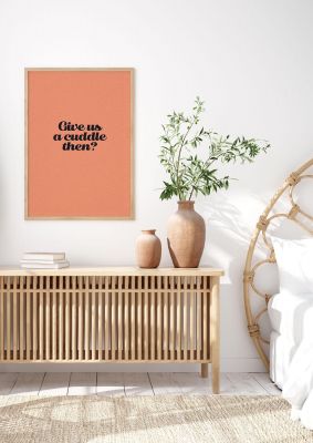 An unframed print of give us a cuddle peach funny slogans in typography in orange and black accent colour