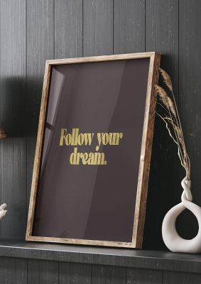 An unframed print of gold inspirational follow your dreams quote in typography in brown and black accent colour